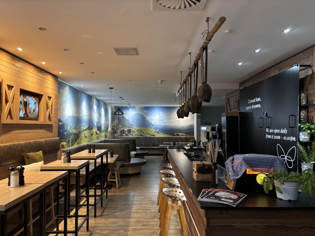 Frühstücken mit Bergpanorama: Der Loungebereich im Cocoon München kombiniert urigen Hütten-Charme mit modernen Design-Elementen.
