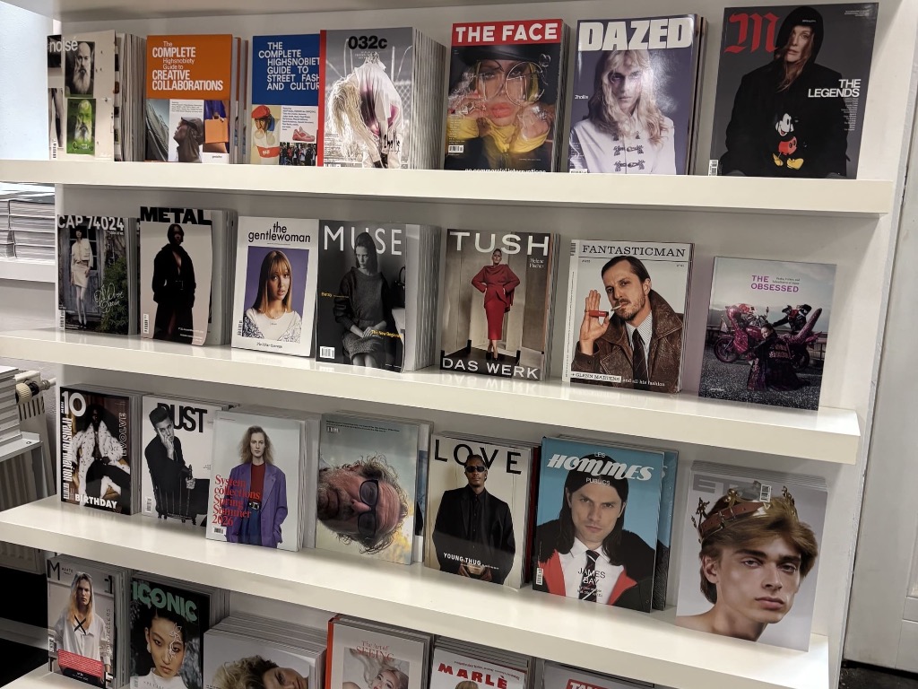 Auslage in einem minimalistischen Magazinladen mit flach präsentierten Independent-Printmedien, Modezeitschriften und Bildbänden im SODA Store München.